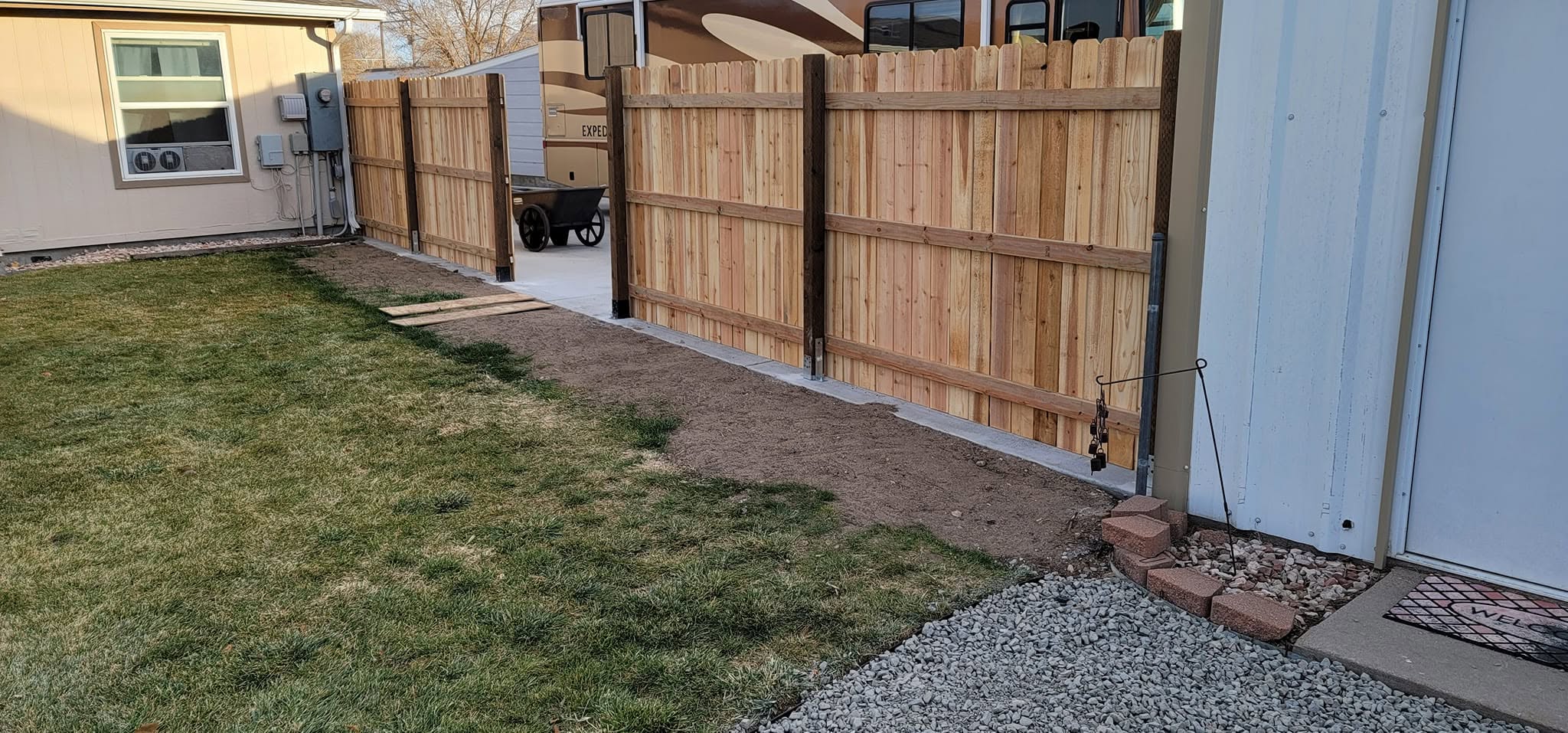Completed residential landscape with wooden fence gates and gravel pathway