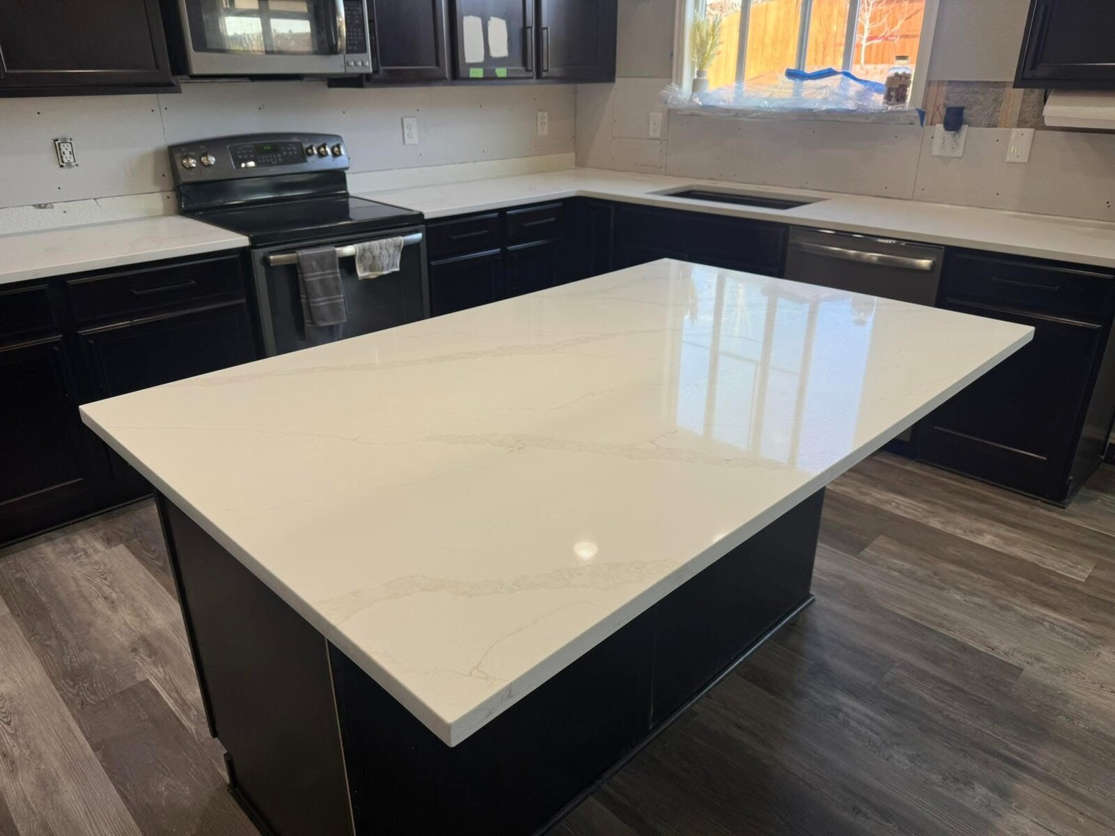 White quartz island in dark-cabinet kitchen
