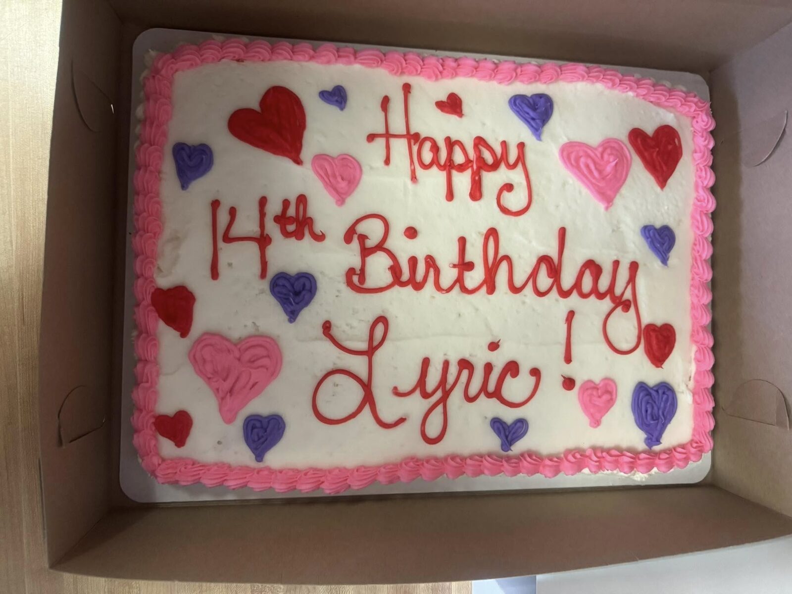 Pink frosted birthday cake with heart decorations