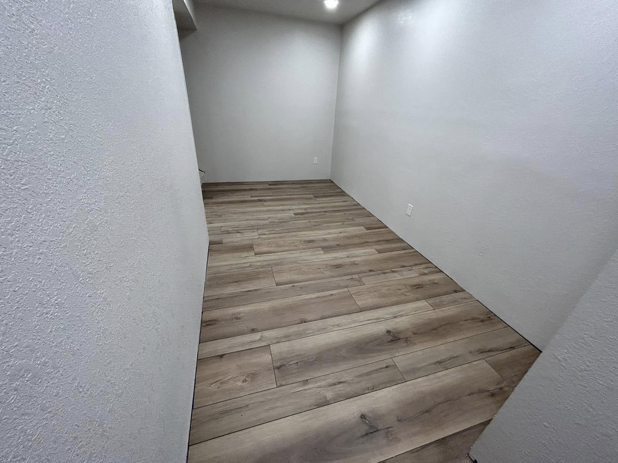 Hallway with light wood-tone plank flooring and white drywall