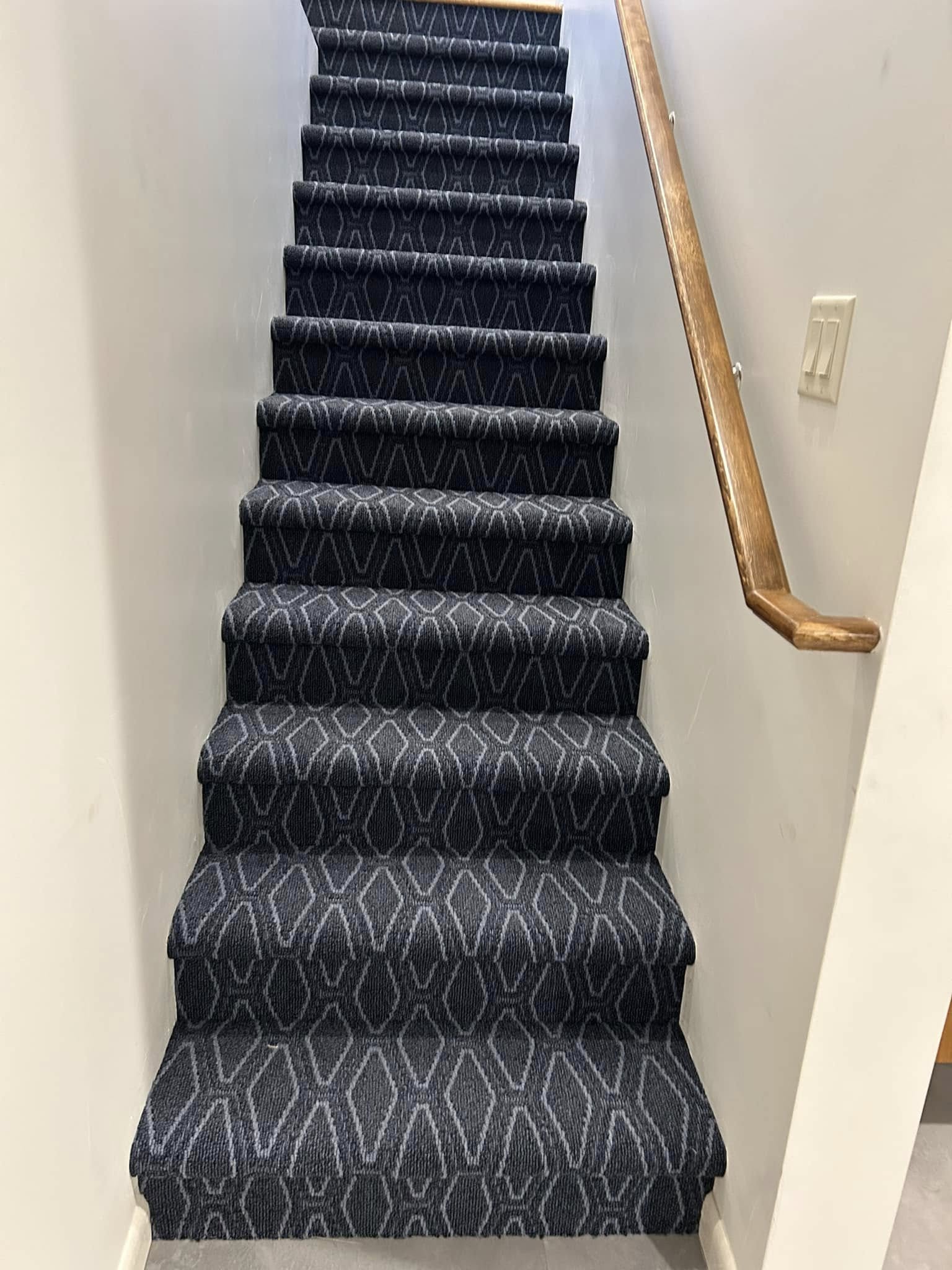 Staircase with dark geometric-patterned carpet runner