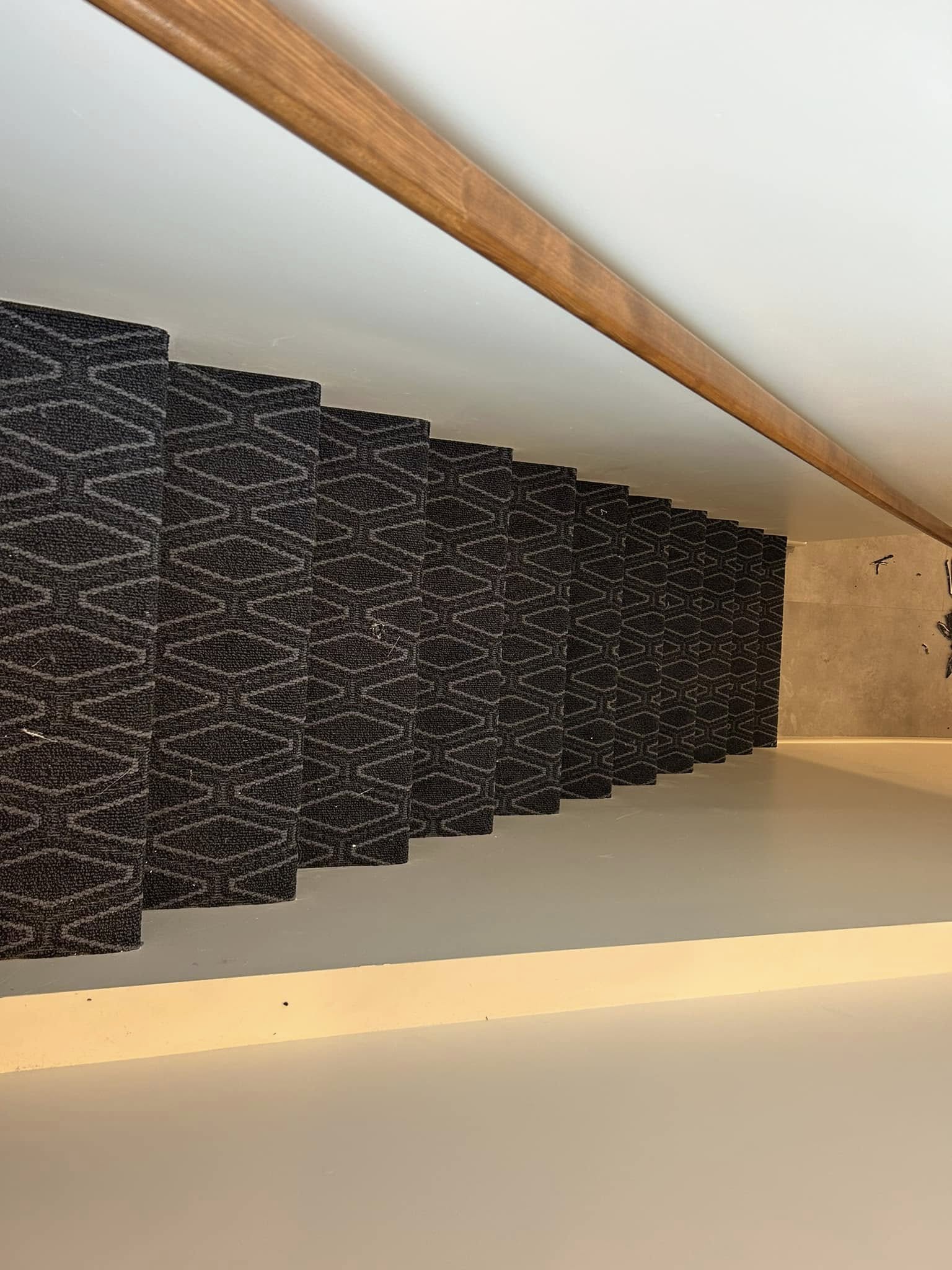 Staircase landing with dark patterned carpet and wooden trim