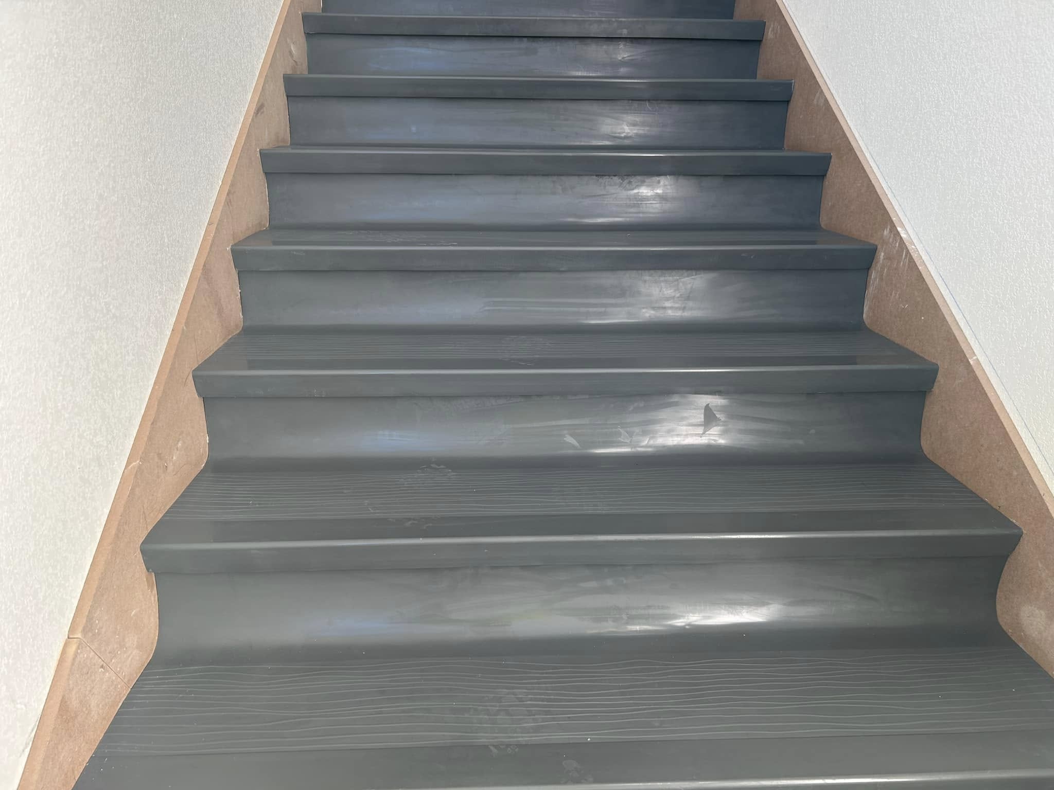 Staircase with gray plank flooring on treads and risers